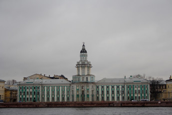 The Kunstkamera Museum, With Its Distinctive Baroque Architecture And Tower, Stands Along The Neva River Embankment On A Cloudy Day In St. Petersburg, Russia.