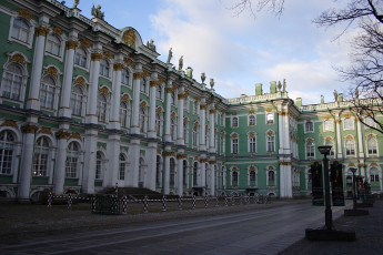 The Winter Palace In St. Petersburg, Russia, Flaunts Its Ornate Baroque Façade With Rich Green And White Colors, Intricate Gold Embellishments, And Grand Windows, Under A Clear Blue Sky