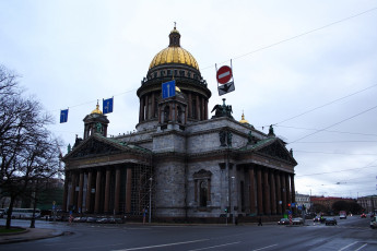 St. Isaac'S Cathedral Dominates The Skyline With Its Grand Dome And Neoclassical Architecture, As Flags Flutter Above A Dampened Street In St. Petersburg, Russia.