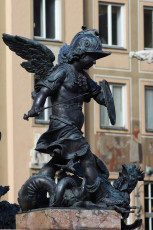 Bronze Statue In Munich Of A Winged Cherub Dressed As A Roman Soldier, Complete With Helmet And Shield, Triumphing Over A Vanquished Mythical Beast.
