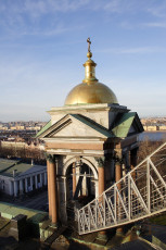 An Architectural Dome With A Golden Spire Sits Atop A Classical Building, Bathed In Soft Sunlight, With A Sweeping View Of St. Petersburg Stretching Into The Horizon Under A Clear Blue Sky.