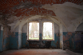 A Room With A Daugavgrīva Window Overlooking A Brick Wall.