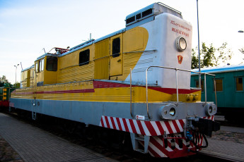 A Train From The Museum, Colorfully Adorned In Yellow And White, Resting On The Tracks.