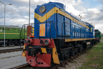 A Train Museum Exhibit Showcasing A Vibrant Blue And Yellow Locomotive On The Tracks.