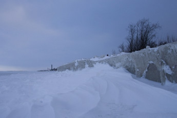 A Frozen Coastline With A Lighthouse In Daugavgrīva During Winter.