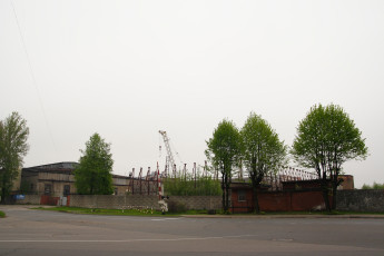 A Picturesque Street In Iļģuciems Adorned With Trees And A Crane At A Distance.