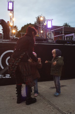 A Woman And Two Children Standing In Front Of A Stage During The Dzelzs Vilks Ielīgo '09 Event.