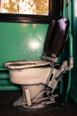 A Train Museum Exhibit Featuring A Toilet In A Room With Green Walls.
